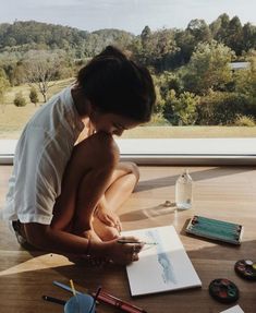 a woman is sitting on the floor writing