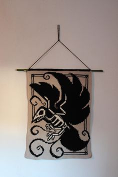 a crocheted wall hanging with a black and white image of a squirrel on it