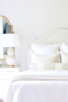 a bed with white sheets and pillows in a bedroom