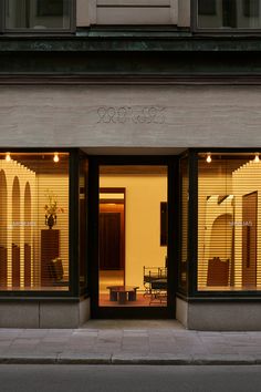 the store front of a building with large windows on both sides and chairs in the window