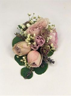 a bouquet of pink flowers and greenery on a white surface