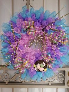 a wreath is hanging on the door with purple and blue ribbons around it's edges