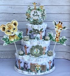 a three tiered baby shower cake decorated with giraffes and other animals