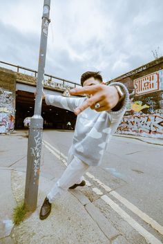 a young man is practicing his martial moves on the street corner in front of a graffiti covered wall