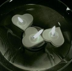 three lit candles sitting on top of a glass plate