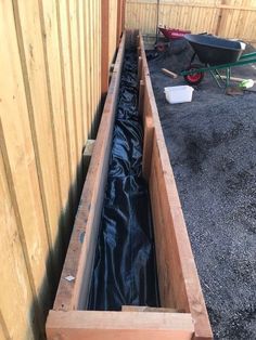 a wooden box filled with black tarp next to a fence