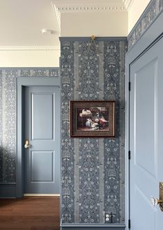 an empty hallway with blue doors and wallpaper on the walls, in front of a painting