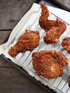 four fried chicken pieces on a cooling rack