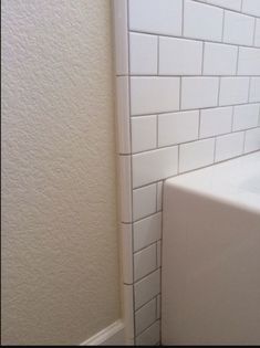 the corner of a bathroom with a white toilet and bathtub next to a wall