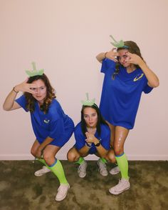 three girls in blue shirts and green socks posing for the camera with their hands up