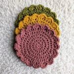 four crocheted coasters sitting on top of a white surface