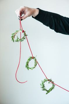 a woman is holding two wreaths with red string attached to the ends, while another person holds them in their hand