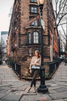 a woman leaning on a lamp post in front of a building