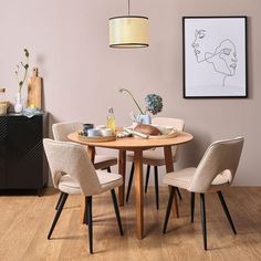 a dining room table with four chairs and an art piece on the wall behind it