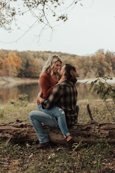 a man and woman sitting on top of a log