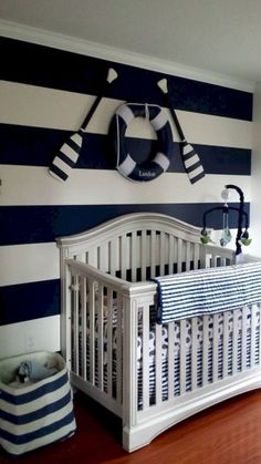 a white crib in a room with blue and white stripes on the wall behind it