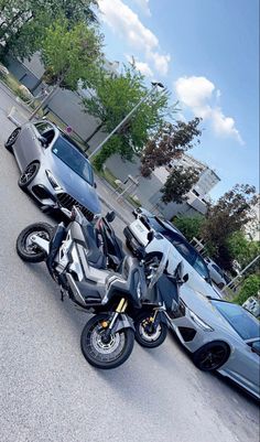 three motorcycles parked next to each other on the side of the road in front of cars