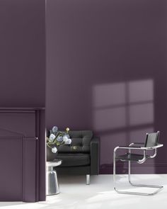 a living room with purple walls and a black leather chair in front of the couch