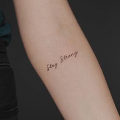 a woman's arm with the word stay strong written on it in cursive font