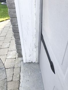 an open door with a black handle on the side of it next to a brick walkway