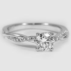 a white gold engagement ring with a twisted band and a round diamond center stone in the middle