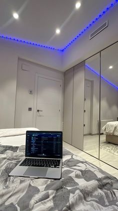 a laptop computer sitting on top of a bed in a room with mirrors and lights