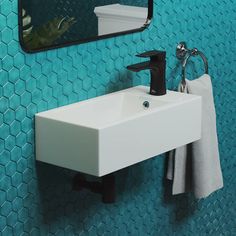 a white sink sitting under a bathroom mirror next to a towel dispenser