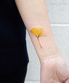 a small yellow leaf on the wrist is shown in front of a woman's arm