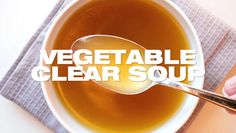 a person holding a spoon over a bowl of soup with the words vegetable clear soup