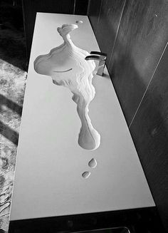 a white sink sitting on top of a counter next to a wooden wall mounted faucet