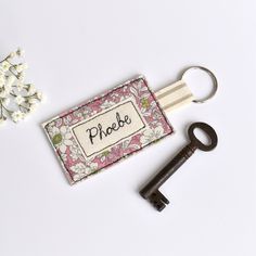 a keychain with a name on it sitting next to a bunch of flowers