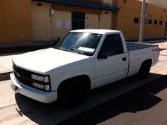 a white truck is parked on the side of the road in front of a building