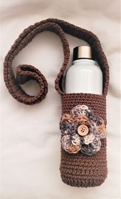 a crocheted bag with a water bottle in it and a flower on the side