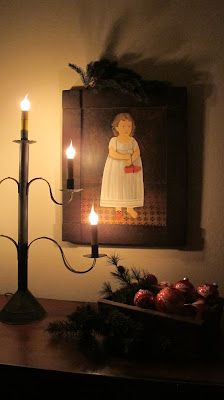 a candle is lit in front of a painting on the wall next to a christmas tree