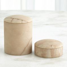 two marble containers sitting on top of a white counter next to each other, one with a lid