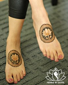 a woman's feet with henna tattoos on them and flowers in the middle