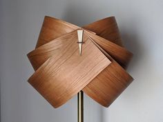 a wooden lamp on a metal stand with a white wall in the background