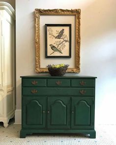 a green dresser with a painting on the wall above it