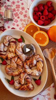 two bowls filled with pastries next to oranges and strawberries on a table