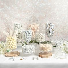 a table topped with lots of white and pink candies next to a vase filled with flowers