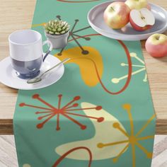 a table topped with plates and cups filled with fruit next to an empty plate on top of a wooden table