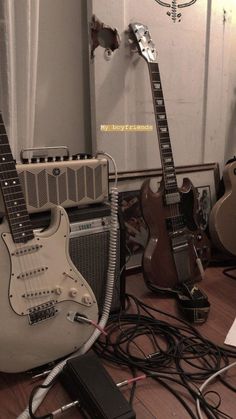 guitars and amps sitting on the floor in front of a mirror