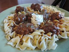 a green plate topped with pasta and meatballs