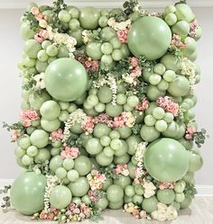 a bunch of balloons that are on top of each other with flowers and greenery