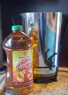 a bottle of apple cider sitting on top of a counter next to a blender