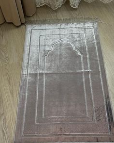 an area rug on the floor in front of a window with curtains and laces