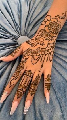 henna tattoo on the palm of a woman's hand with flowers and leaves