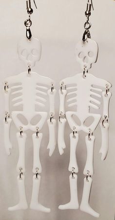 Hand-crafted Pierced Earrings Unique and One-of-a-Kind Skeleton Earrings Approximately 3-3/4" long x 1-1/8" wide Featuring resin skeleton bones, hand-assembled with stainless jumping. They are lightweight and elegant and are set with high quality, stainless, hypoallergenic, ear wires. Carded. Made in a clean, smoke free, pet free and temperature controlled studio. Ready to ship immediately. Gothic White Dangle Jewelry, White Gothic Dangle Jewelry, White Gothic Handmade Earrings, Handmade White Gothic Earrings, Halloween Skull Jewelry In Bone Color, Halloween Skull Shaped Bone Jewelry, Handmade Bone Jewelry For Halloween, White Gothic Skull Jewelry, White Skull Jewelry For Day Of The Dead