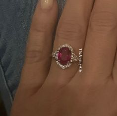 a woman's hand with a ring on it and a red stone in the middle