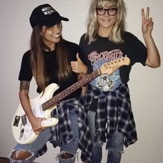 two women standing next to each other holding guitars and giving the peace sign with their fingers